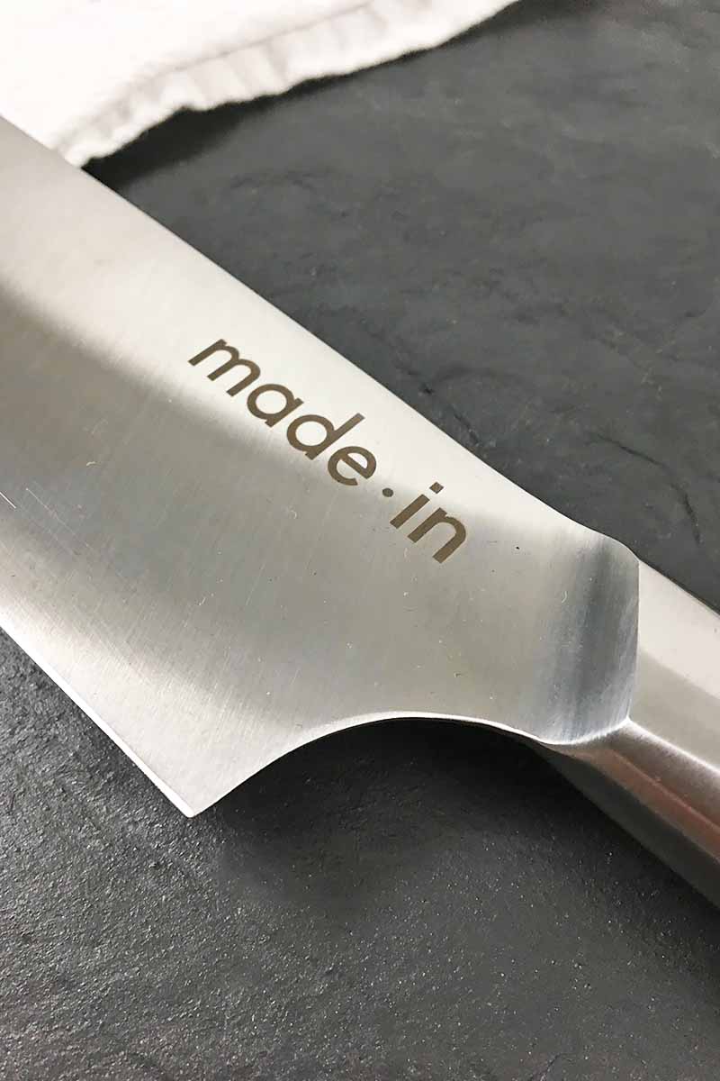 Vertical close-up image of the blade of a cutlery item with text.