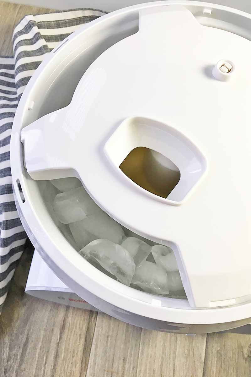 Vertical image of a cover on an ice cream maker next to a striped towel.