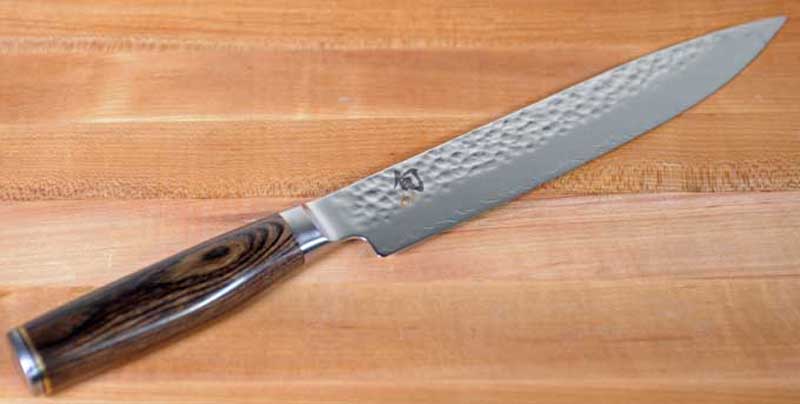 An oblique view of a Shun Premier Sujihiki Slicing Knife on a maple wood table.