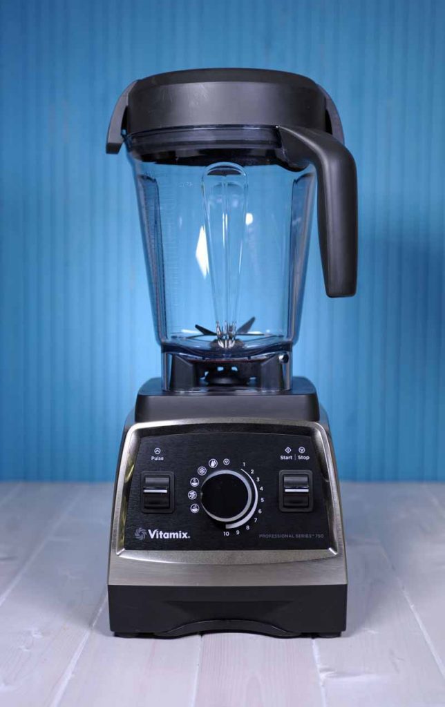 The Vitamix 750 Professional Series Blender sitting on a white painted wooden surface with a blue background.