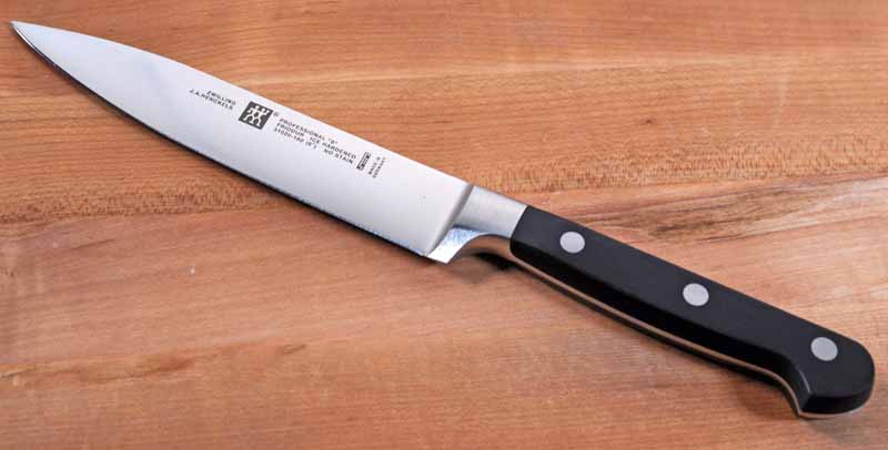 The ZWILLING J.A. Henckels Professional S 6-inch Utility Knife laying on a maple wood cutting board.