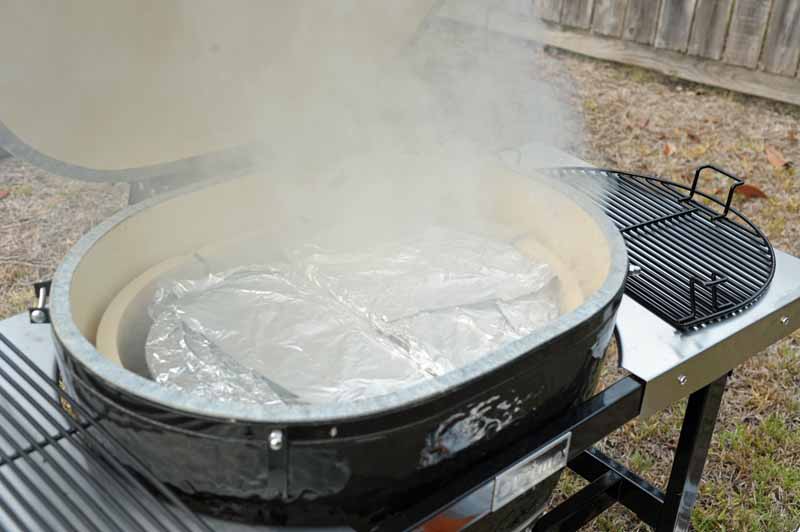 The lid of the Primo XL 400 Ceramic Kamado open, showing the deflector plates wrapped in aluminum foil.