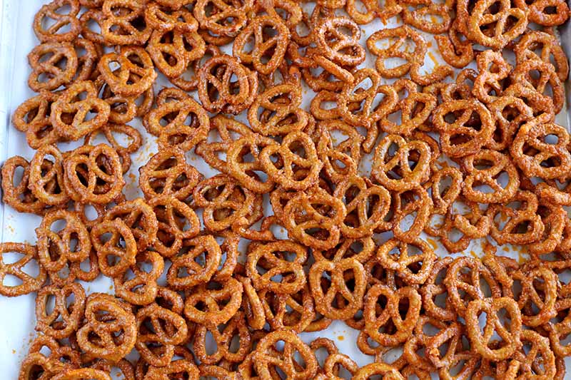 Overhead shot of small, brown, salted and spice-coated pretzels on a baking sheet.