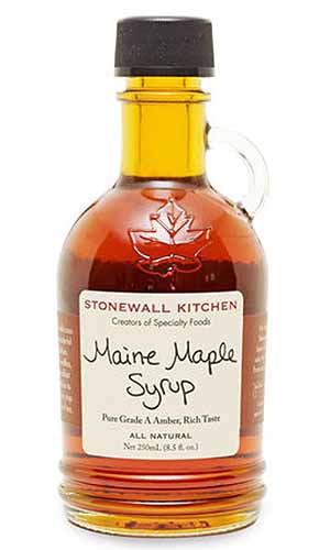 A glass bottle of Maine maple syrup from Stonewall Kitchen, isolated on a white background.