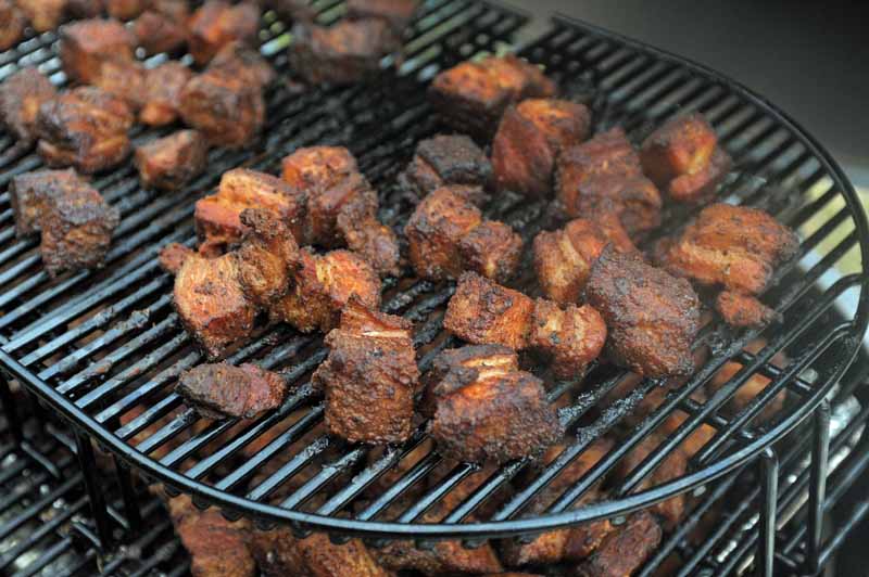 A closeup shot of pork belly burnt ends being prepared on the Primo XL 400 Ceramic Kamado Grill.