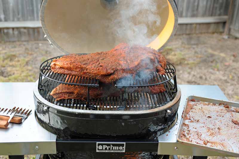 The Primo XL 400 showing the lid open, with two briskets starting to be smoked over indirect heat.