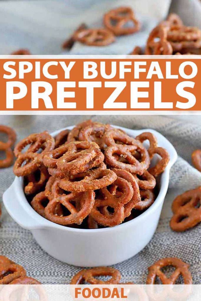 Vertical image of a white ceramic dish of spicy buffalo pretzels, with more scattered around it on a folded and gathered beige cloth, printed with white and orange text.
