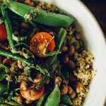 Horizontal image of a dish with asparagus, tomatoes, and snap peas.