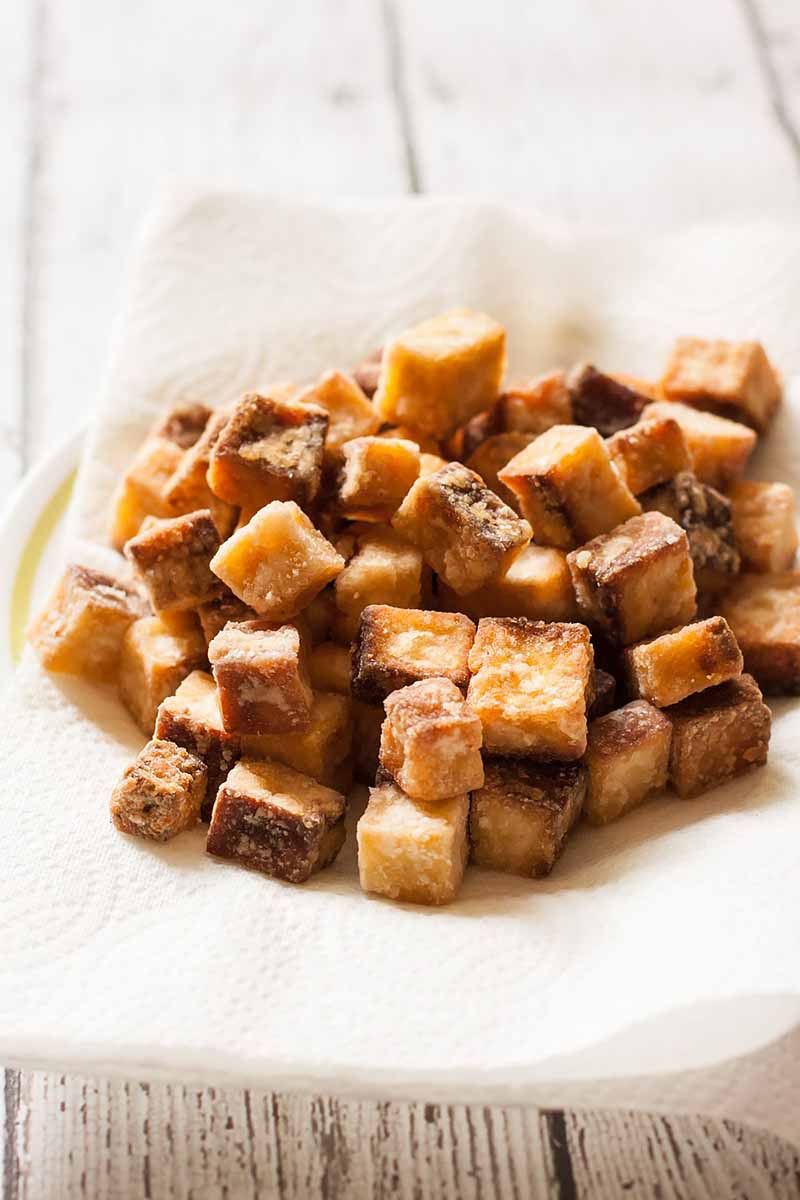 Vertical image of a pile of fried tofu.