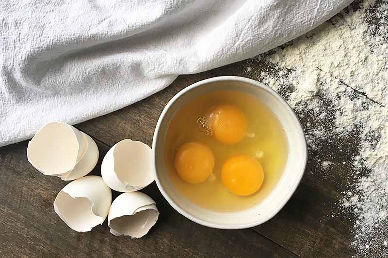 Horizontal image of three eggs in a bowl and their shell