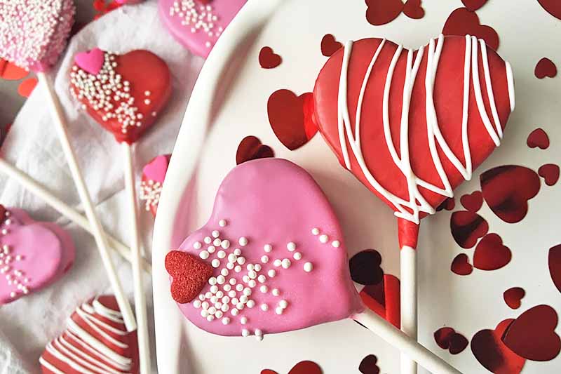 Horizontal close-up image of two treats with Valentine's Day decorations.
