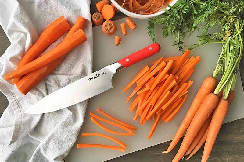 Horizontal image of carrots in various stages of prep with a Made In knife.