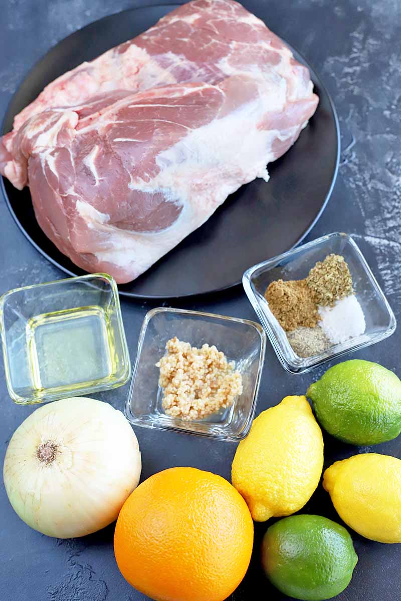 Vertical image of pork, citrus, onion, and assorted ingredients.