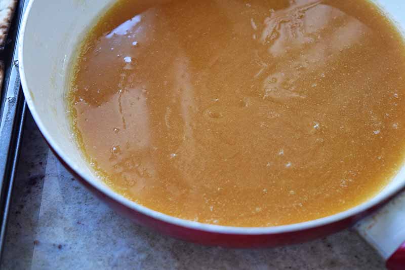Homemade caramel sauce in a frying pan on a metal baking sheet.