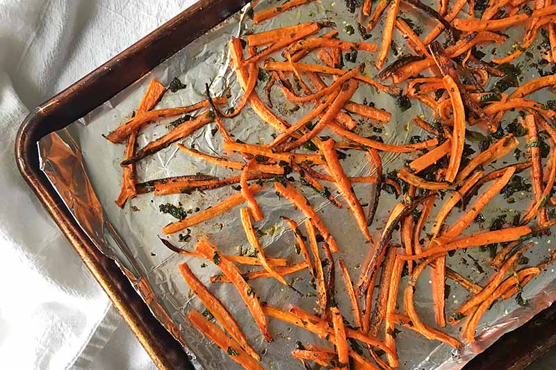 Horizontal image of roasted carrots on a sheet pan.