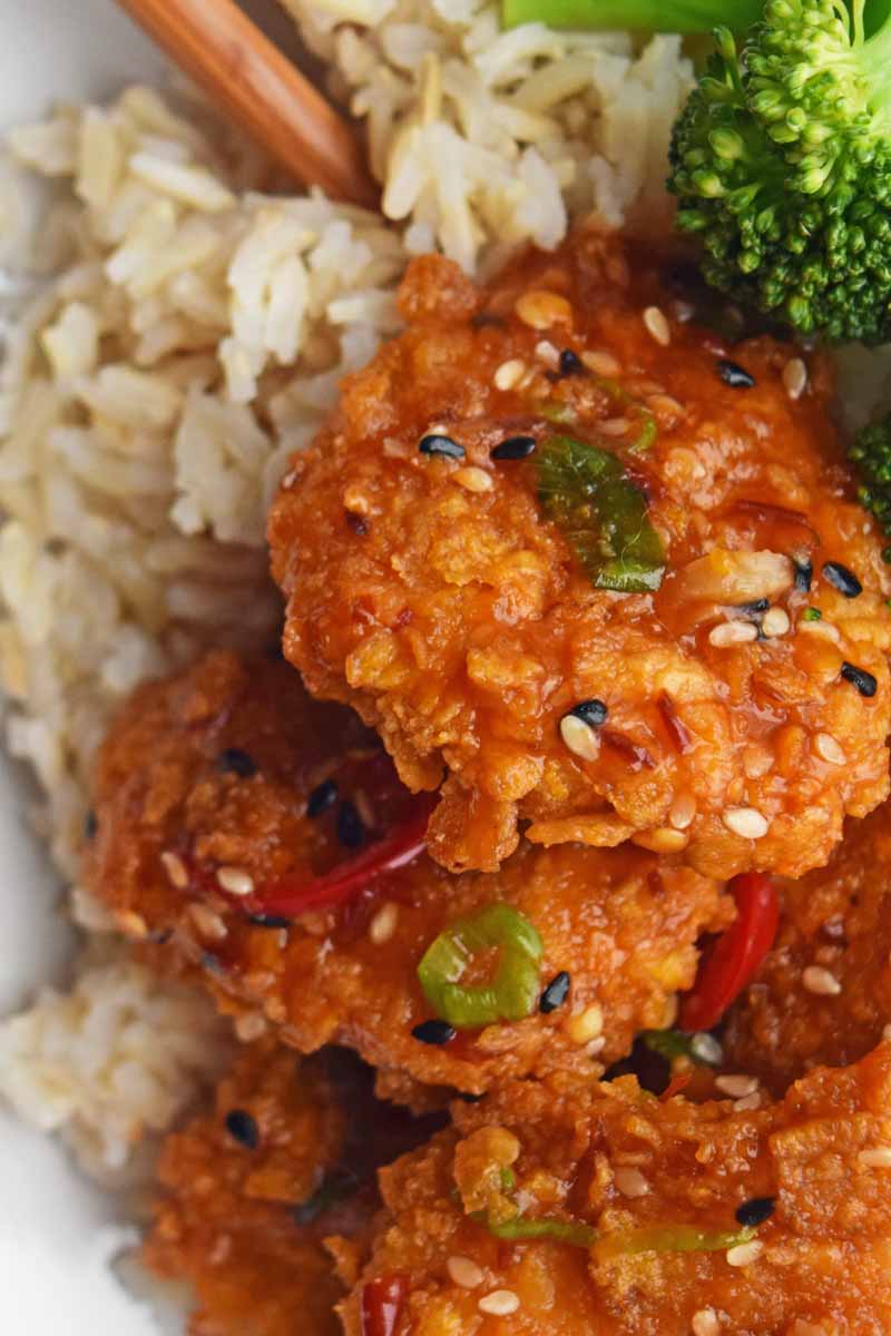 Top down, close up view of a baked General Tso's chicken recipe. Also includes steamed rice and al dente broccoli.