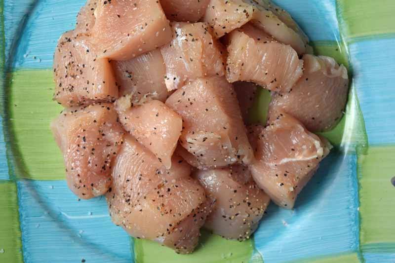 Raw chicken cubes with salt and pepper applied.
