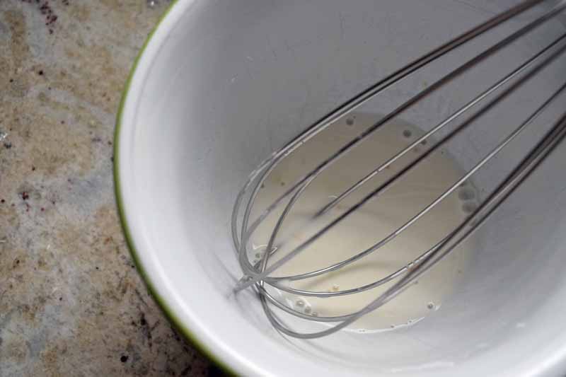 A water and corn starch slurry being whisked in a mixing bowl.