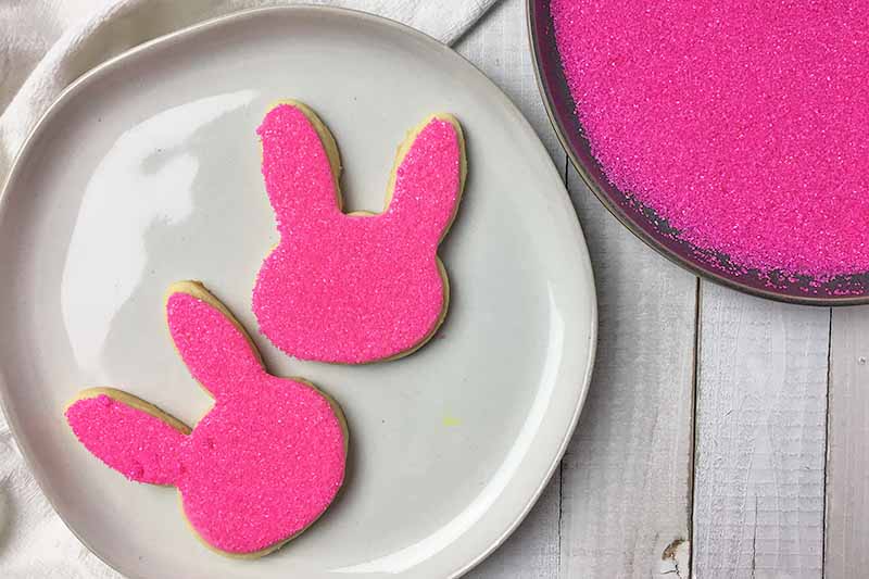Horizontal image of two rabbit-shaped cookies with pink sanding sugar.