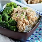 Horizontal image of a brown dish with broccoli florets and shredded chicken with white chopsticks.
