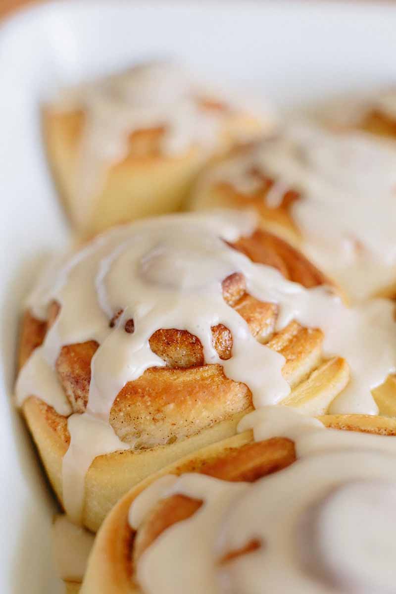 Vertical close-up image of a cinnamon roll with glaze.