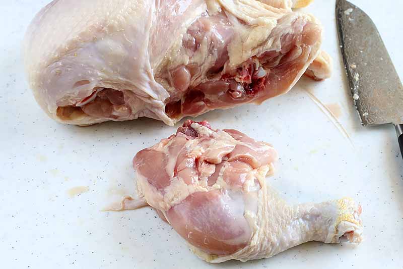 Horizontal image of a raw chicken with the drumstick entirely removed.