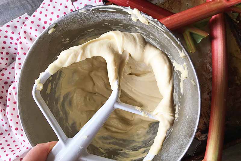 Horizontal image of a paddle holding a creamy batter over a bowl.