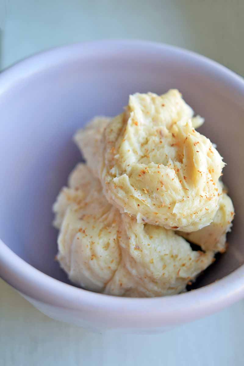 Vertical image of a white bowl with a mound of spiced butter.