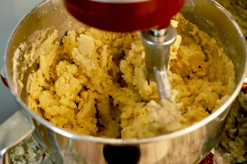 Oblique view of the cookie dough in a stand mixer bowl after the flour was added.