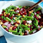 Horizontal image of a large white serving bowl with a bean salad.