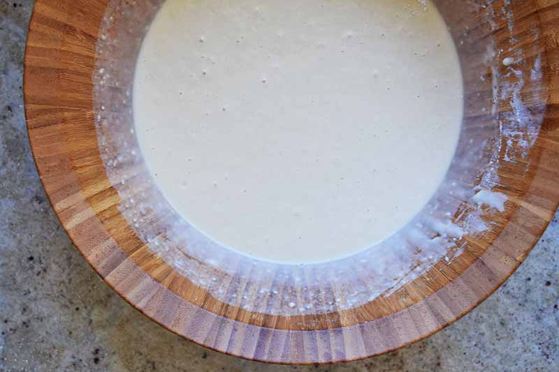 Horizontal image of a light and liquidy batter in a wooden bowl.