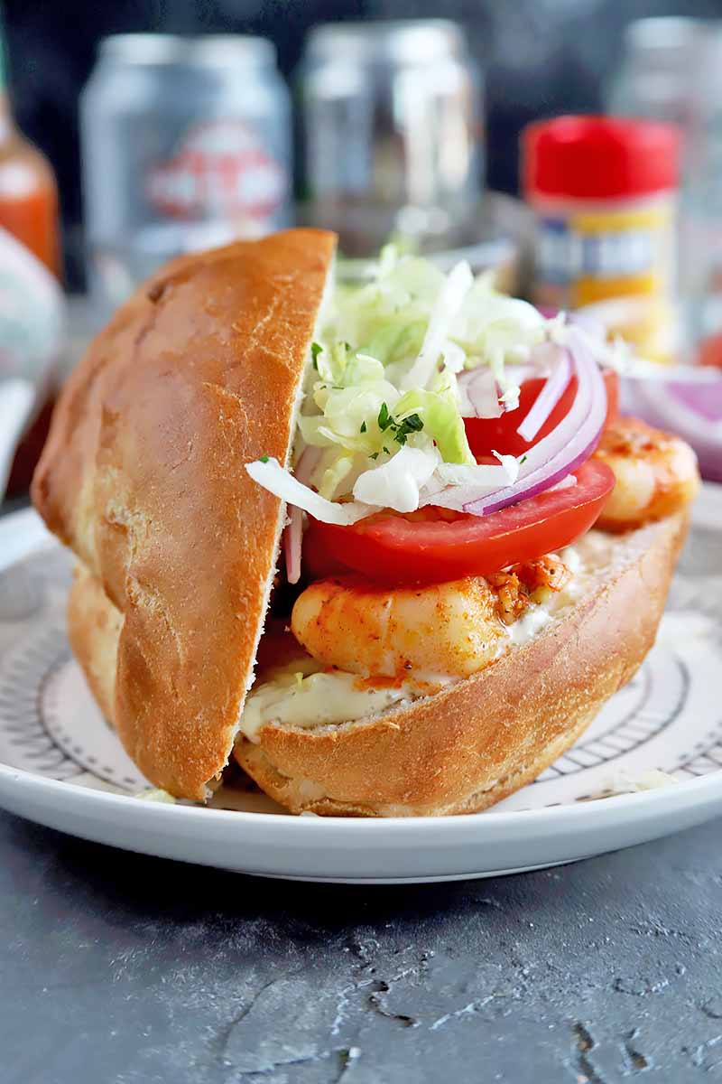 Vertical image of the side of a shrimp po'boy with fresh toppings.