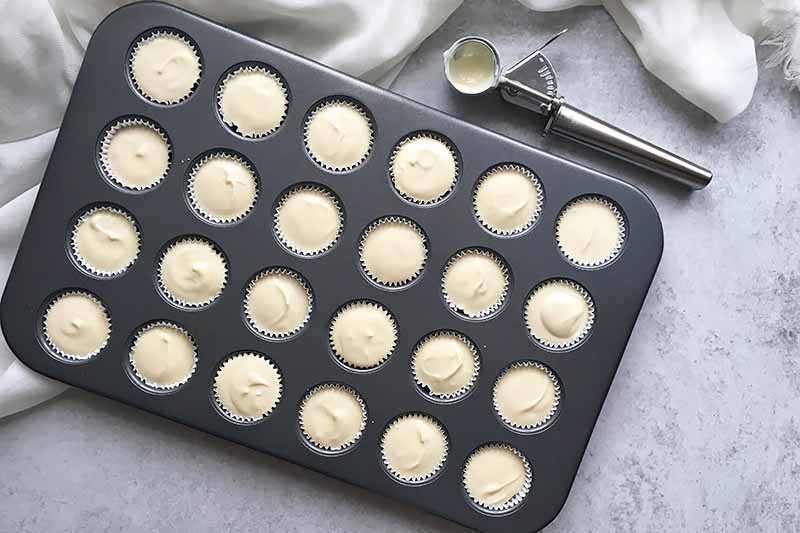 Horizontal image of unbaked cheesecake filling divided in a mini cupcake pan.