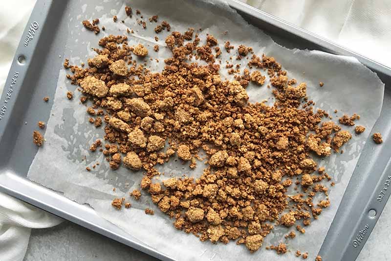 Horizontal image of a crumbly toasted mixture on a baking sheet.