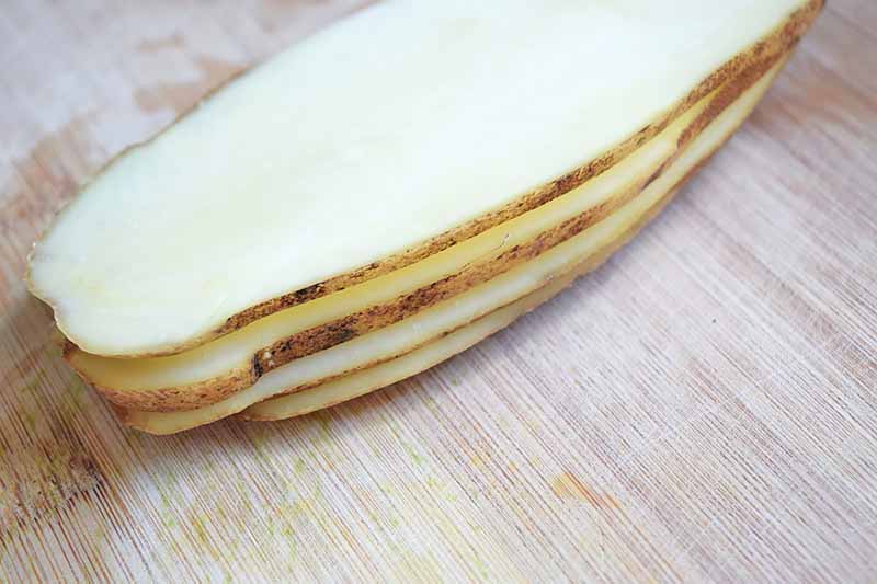 Horizontal image of thinly sliced raw potatoes.