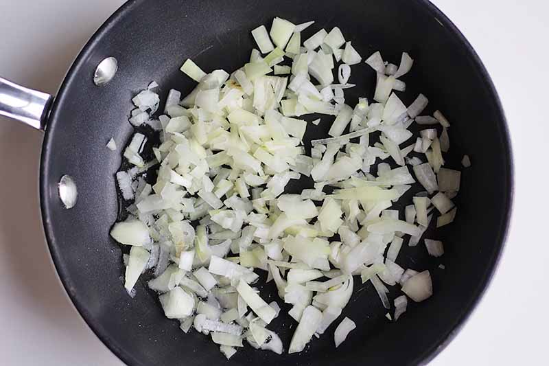 Horizontal image of a pan with lightly caramelized chopped onions.