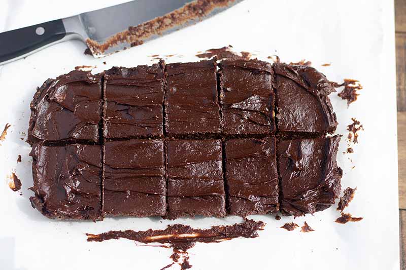 Horizontal image of squares of brownies next to a knife.