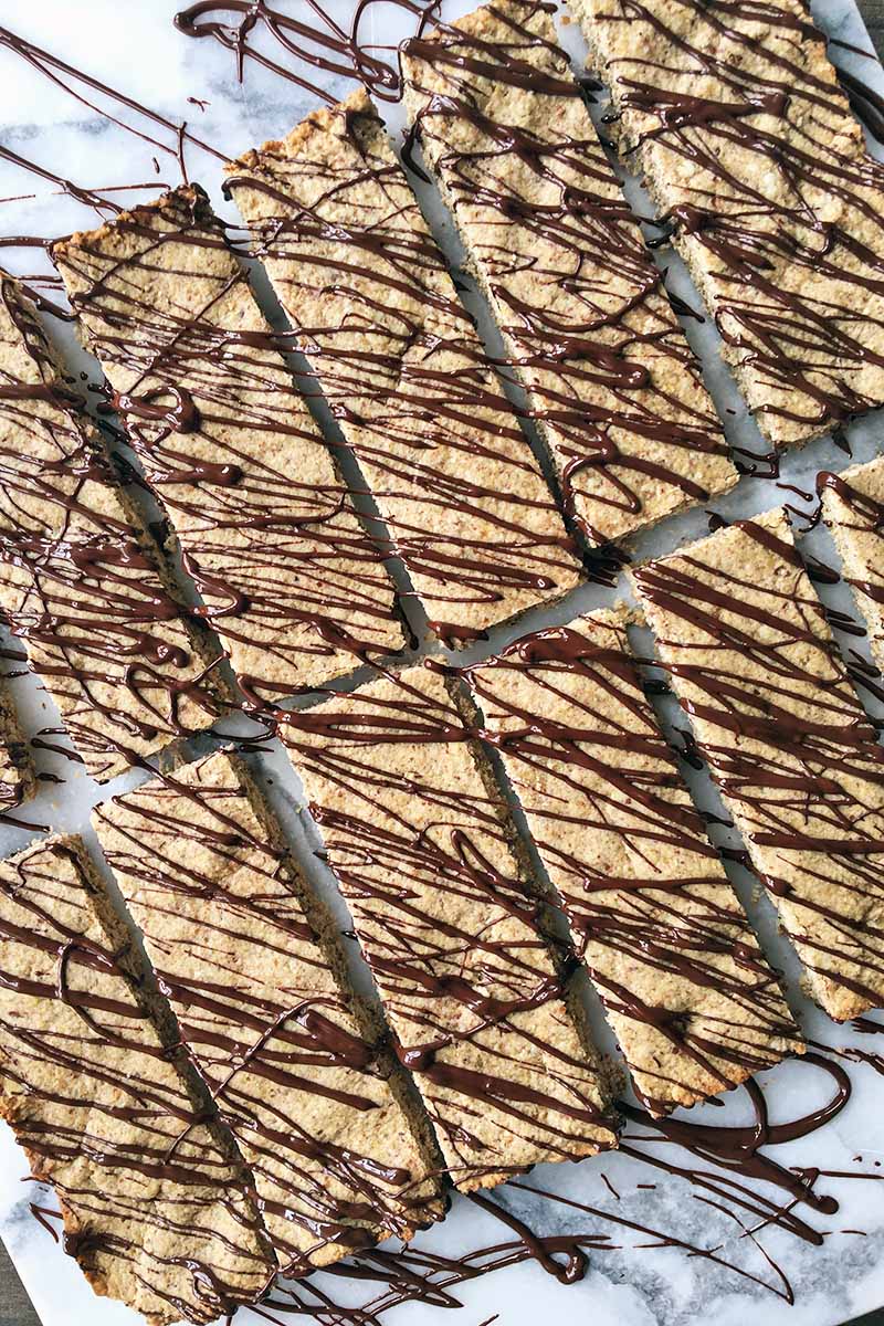 Vertical top-down image of two rows of a rectangular cookie with chocolate drizzle.