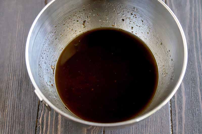 Horizontal image of a bowl of dark brown marinade.