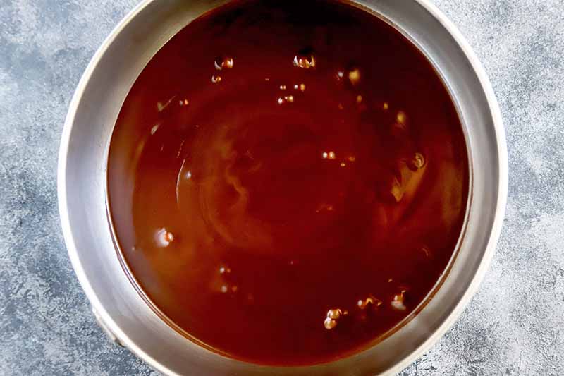 Horizontal image of a pot with a dark brown liquid mixture.