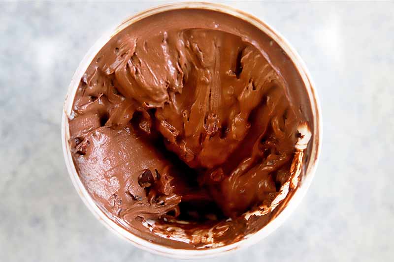 Horizontal image of a frozen dark cocoa dessert in a canister.