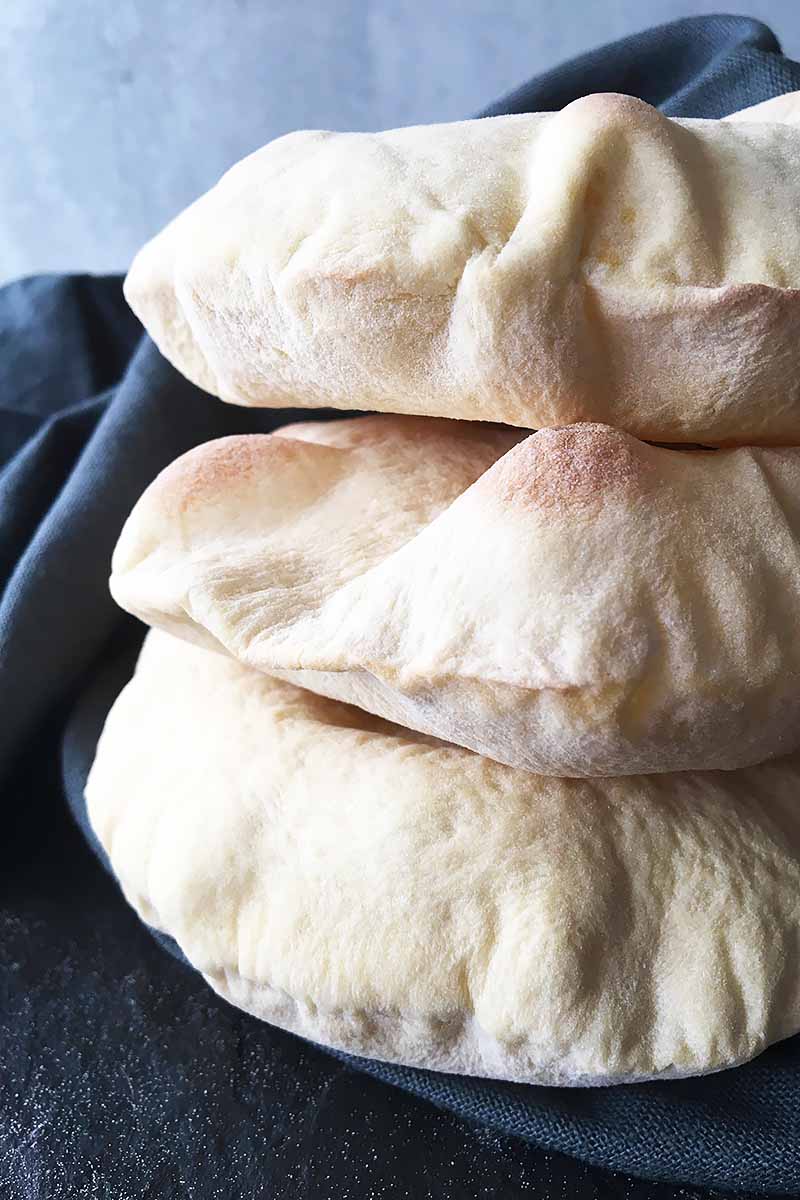 Vertical close-up image of a stack of puffy pita.