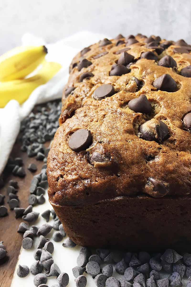 Vertical close-up image of part of a whole banana chocolate chip loaf.