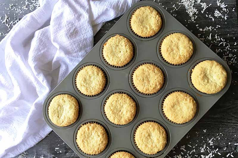 Horizontal image of baked light yellow muffins in a pan.