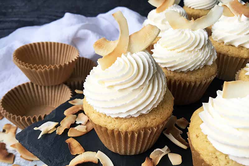 Horizontal image of decorated cupcakes with toasted coconut garnishes.