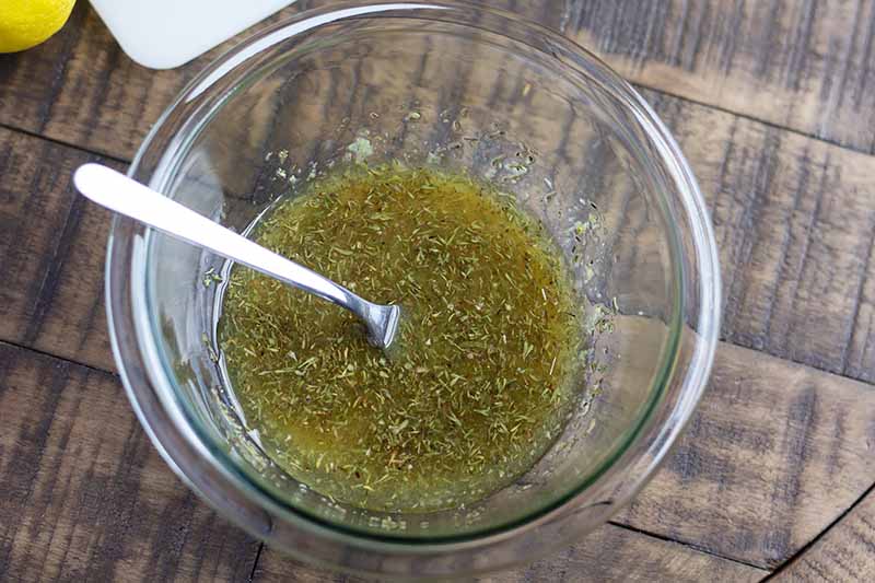 Horizontal image of a glass bowl with a green marinade.