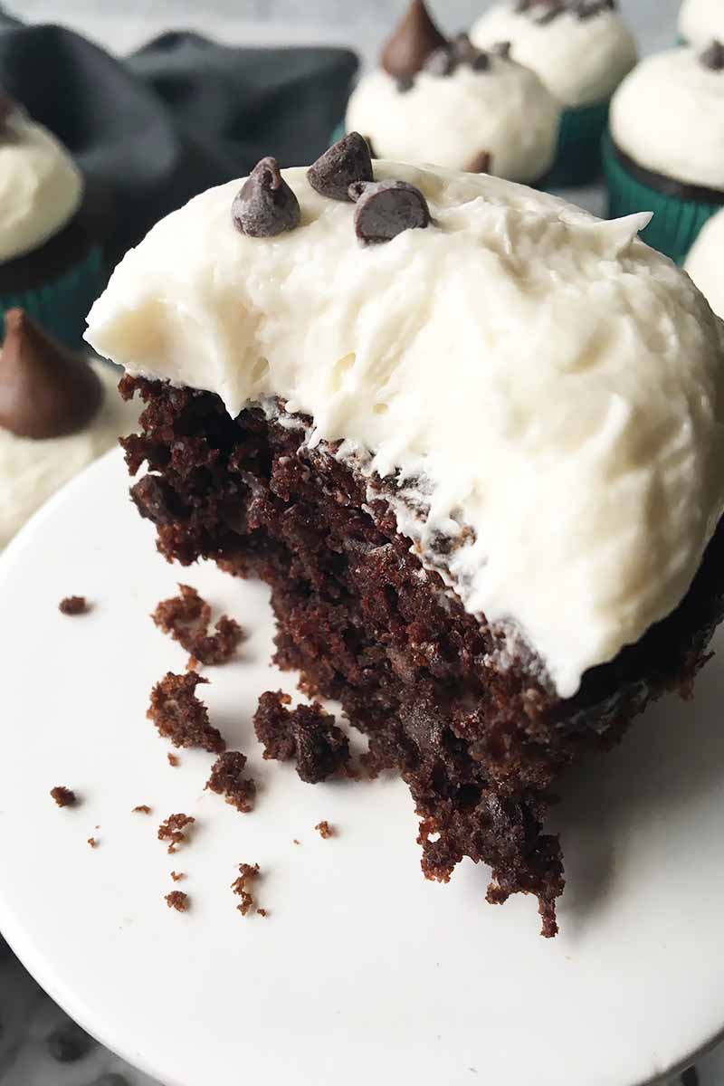 Vertical image of part of a chocolate cupcake with vanilla buttercream.