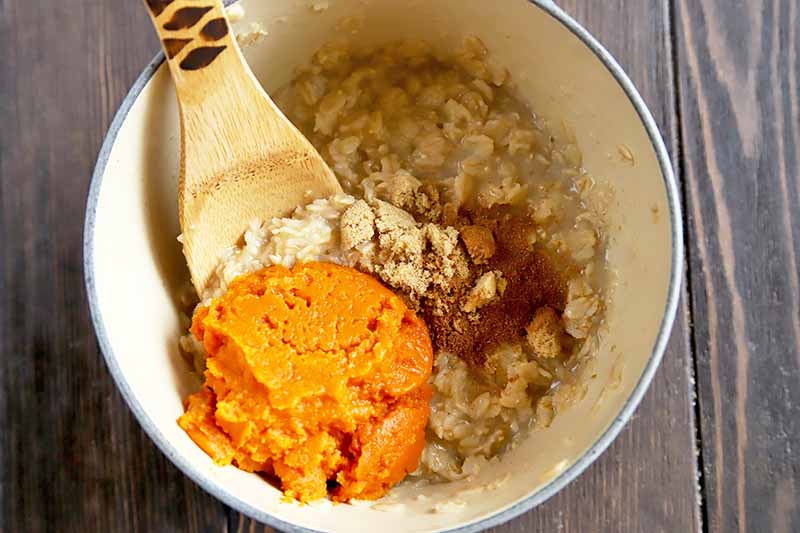 Horizontal image of a pot with oats, squash puree, and spices.