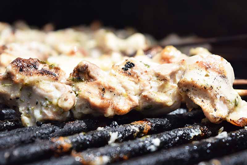 Close-up horizontal image of chicken skewers cooking on the grill.