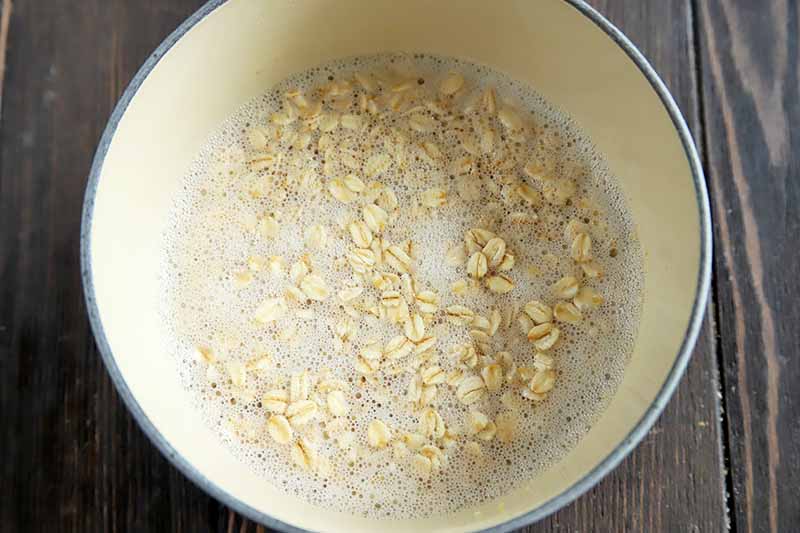 Horizontal image of a pot with milk and uncooked oats.